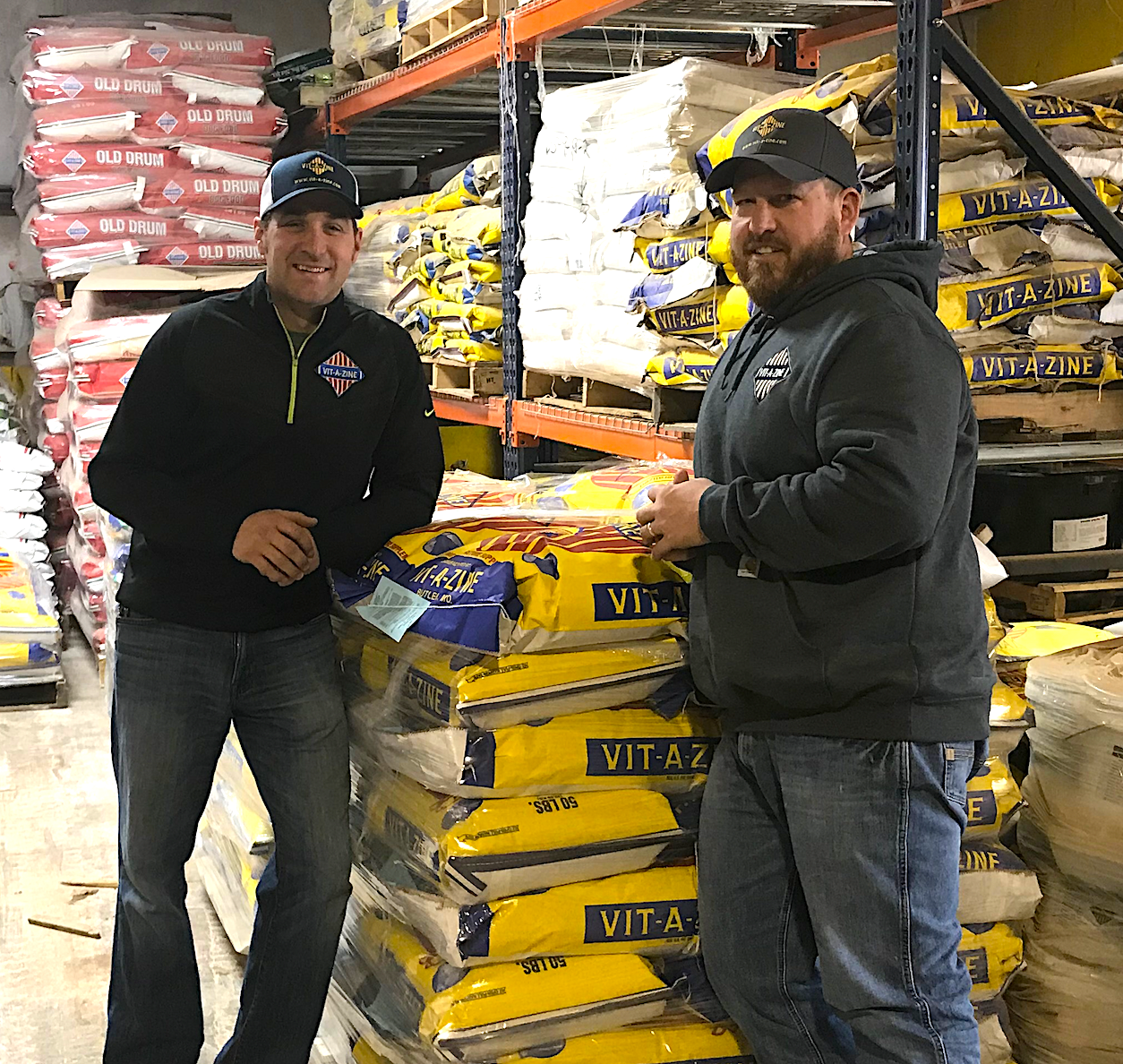 Two men standing in front of a pile of dog food.